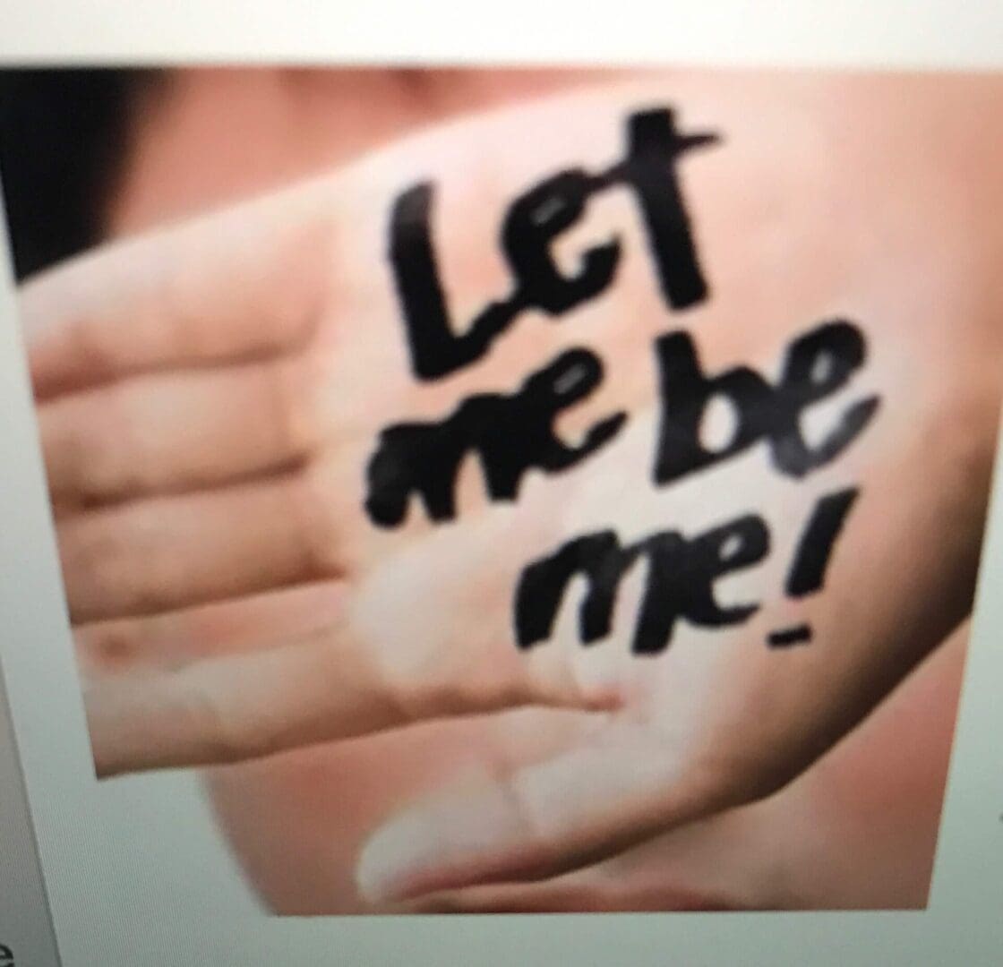 A person 's hand with the words " let me be me !" written on it.